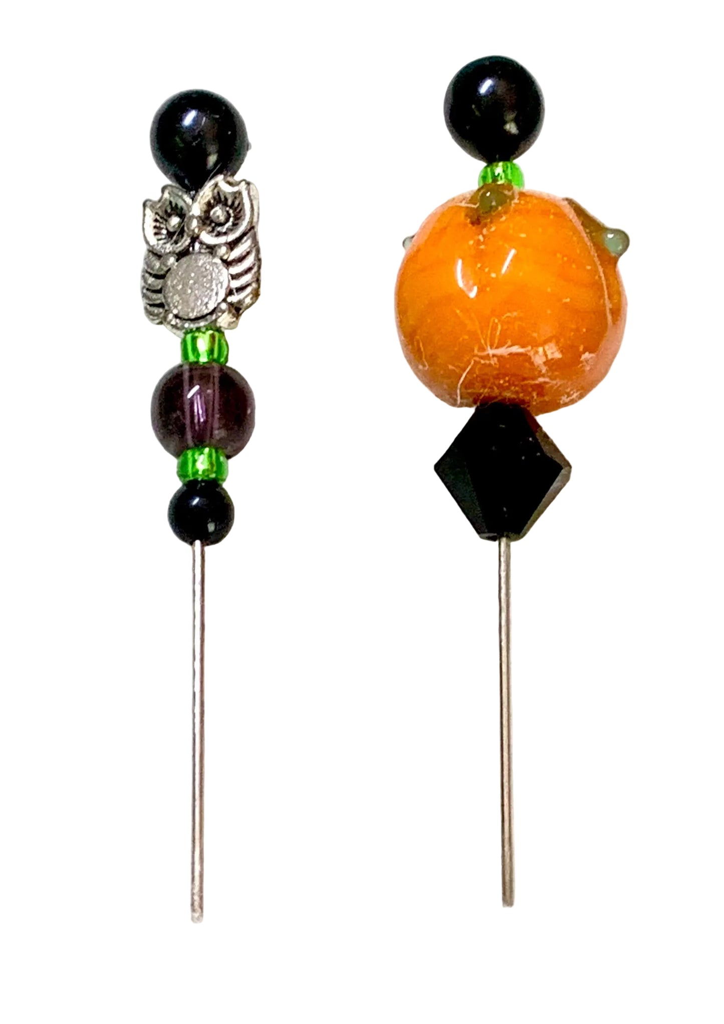 Two beaded pins, displayed on a white background. One pin features a silver owl charm, black beads, and green spacer beads. The other pin is a pumpkin.
[additional_image_link]