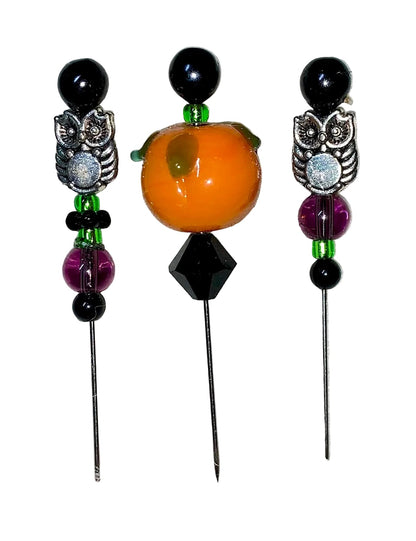 Three decorative  Halloween pins with 1 pumpkin, 2 owls, several green, purple and black glass beads designs on a white background.
[image_link]