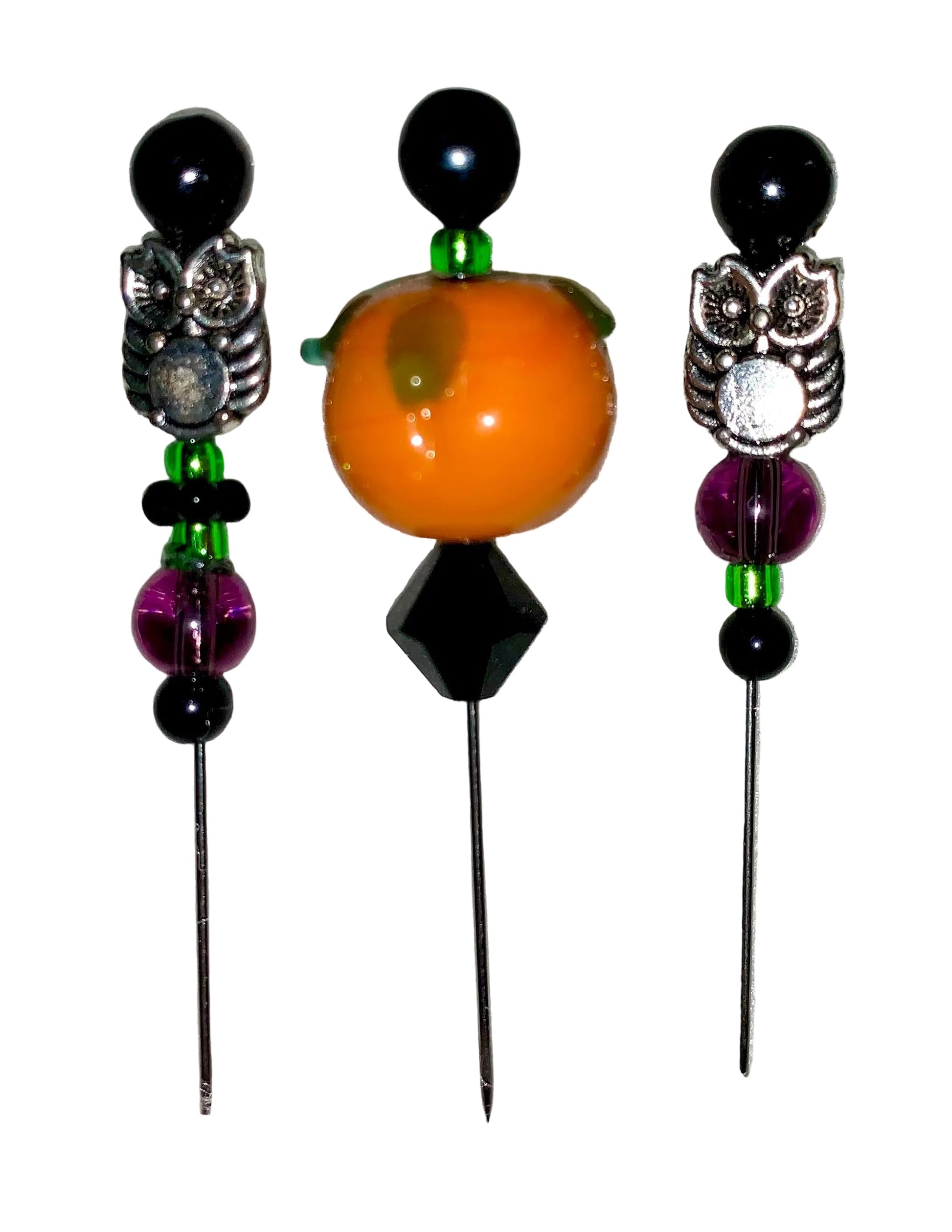 Three decorative  Halloween pins with 1 pumpkin, 2 owls, several green, purple and black glass beads designs on a white background.
[additional_image_link]