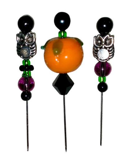 Three decorative  Halloween pins with 1 pumpkin, 2 owls, several green, purple and black glass beads designs on a white background.
[additional_image_link]