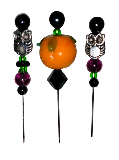Three decorative  Halloween pins with 1 pumpkin, 2 owls, several green, purple and black glass beads designs on a white background.
[additional_image_link]