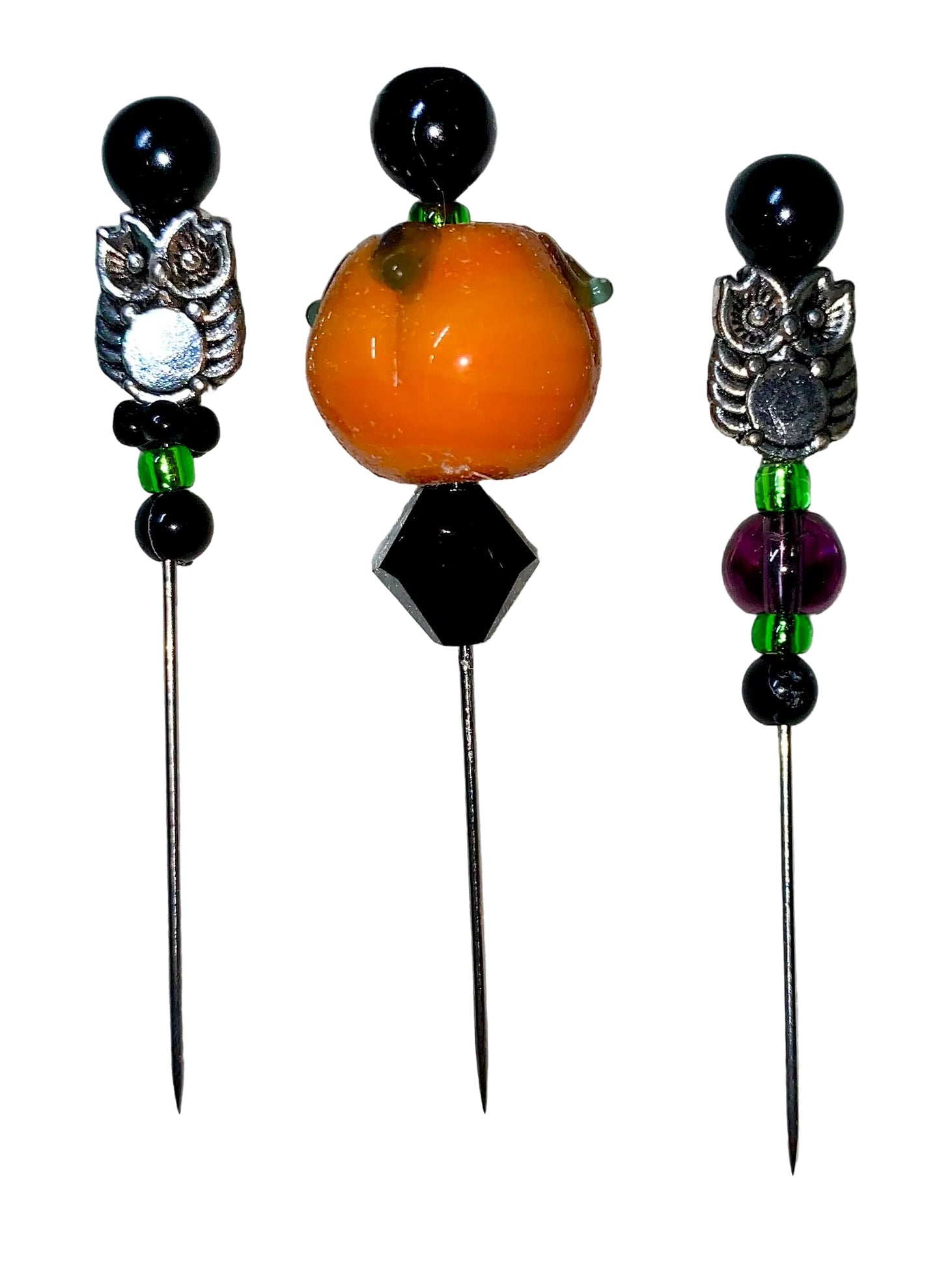 Three decorative  Halloween pins with 1 pumpkin, 2 owls, several green, purple and black glass beads designs on a white background.
[image_link]