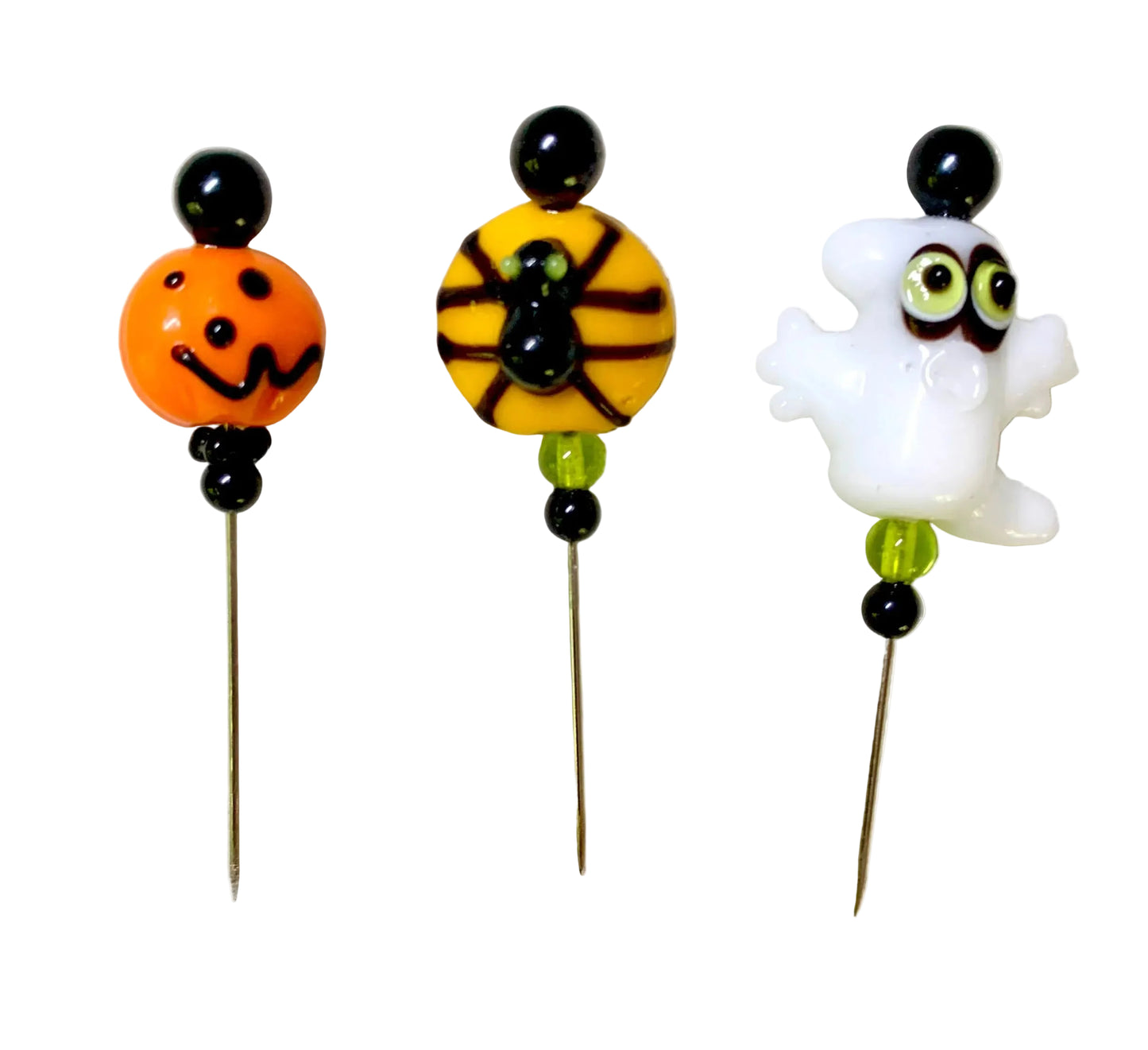 Three Halloween-themed glass beads on metal pins, featuring an orange jack-o'lantern ,a spider on a yellow bead, and a white ghost, displayed on a white background.
[additional_image_link]]
