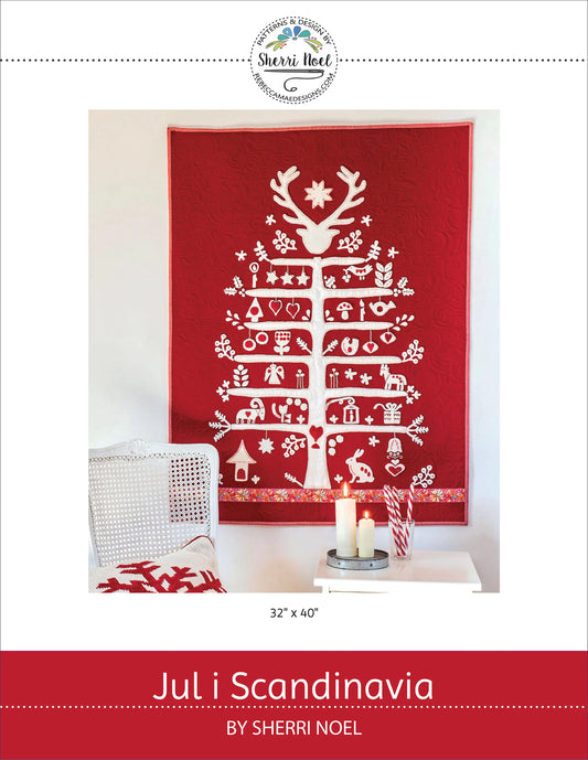 A red quilted wall hanging or textile panel with a white stylized Christmas tree design and holiday motifs, shown in a styled interior scene with candles and a chair. The image includes branding for Sherrl Noel and the title 'Jul i Scandinavia'.
Photo by Rebecca Mae Designs [image_link]