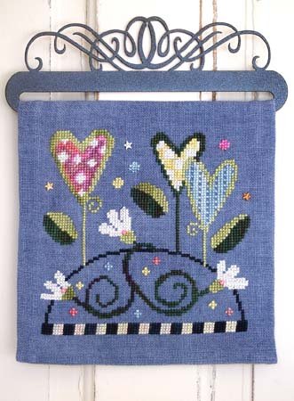 Embroidered wall hanging with floral design on a blue background.
Photo by SamSarah Studio Designs [additional_image_link]