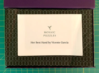 A boxed puzzle product shown from above on a green cutting mat. The top of the box is purple, and the inner lid has a dark olive-green patterned surface.
Photo by Karen King [additional_image_link]