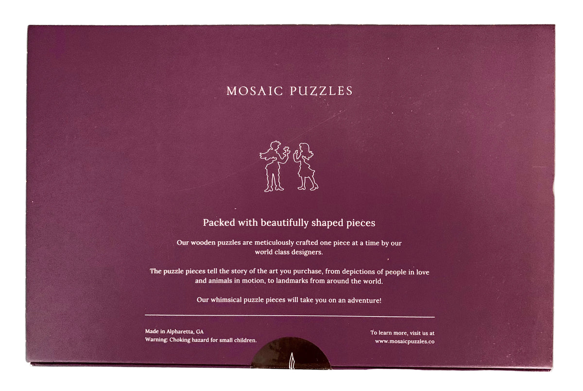 The back of a purple Mosaic Puzzles gift box, showing product description text and a small line drawing of two children assembling a puzzle, placed on a green cutting mat.
Photo by Karen King [additional_image_link]
