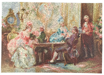A completed jigsaw puzzle showing a classical painting of several people in ornate 18th-century clothing gathered around a table in an elegant interior. The puzzle pieces are fully assembled, and the artwork fills nearly the entire frame.
Photo by Karen King [additional_image_link]