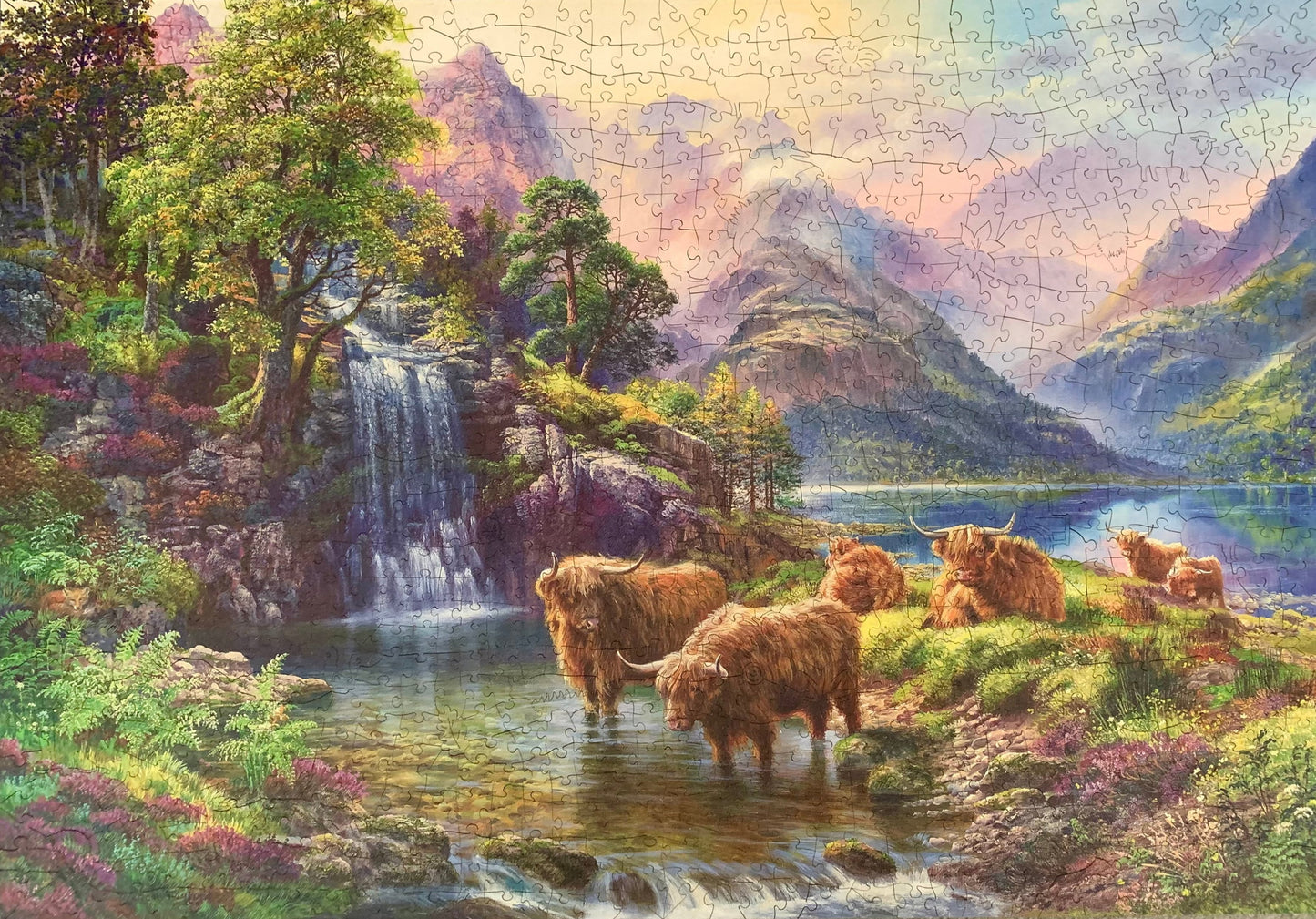 A wooden jigsaw puzzle depicting a highland landscape scene with cows, a waterfall, and mountains in the background.
Photo by Karen King [additional_image_link]