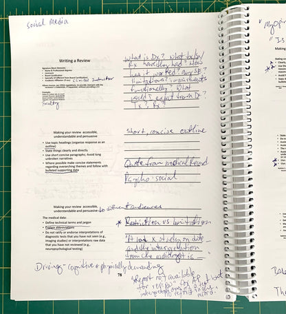 An open spiral-bound notebook showing handwritten notes and printed text pages, photographed on a green cutting mat background.
[additional_image_link]
