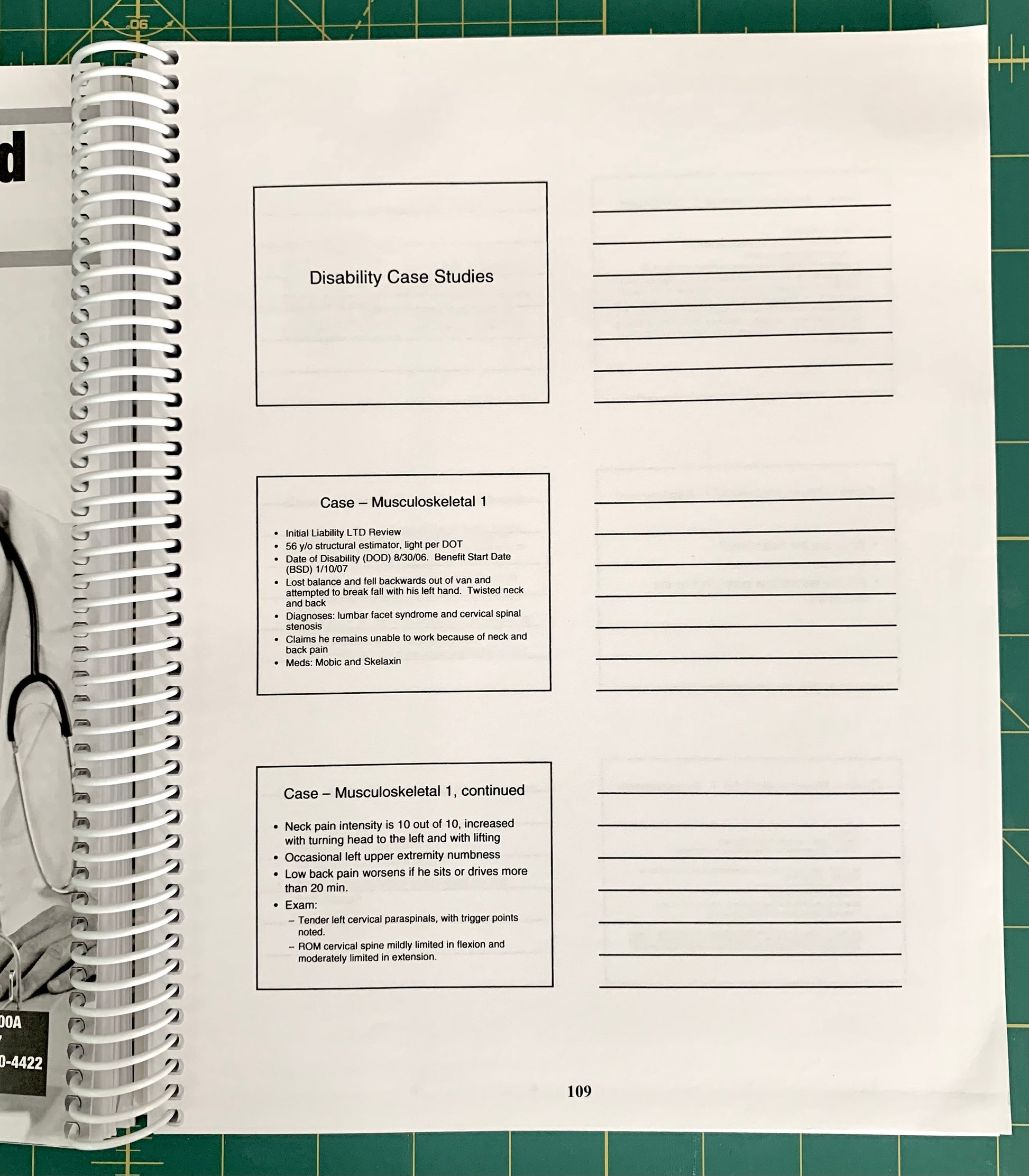 A spiral-bound notebook page titled 'Disability Case Studies' with lined writing space and printed case study text, photographed on a green cutting mat with part of a person's hand and arm visible at the left edge.
[additional_image_link]