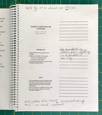 A spiral-bound notebook page with printed text about disability consulting for physicians and handwritten notes, photographed on a green cutting mat.
[additional_image_link]