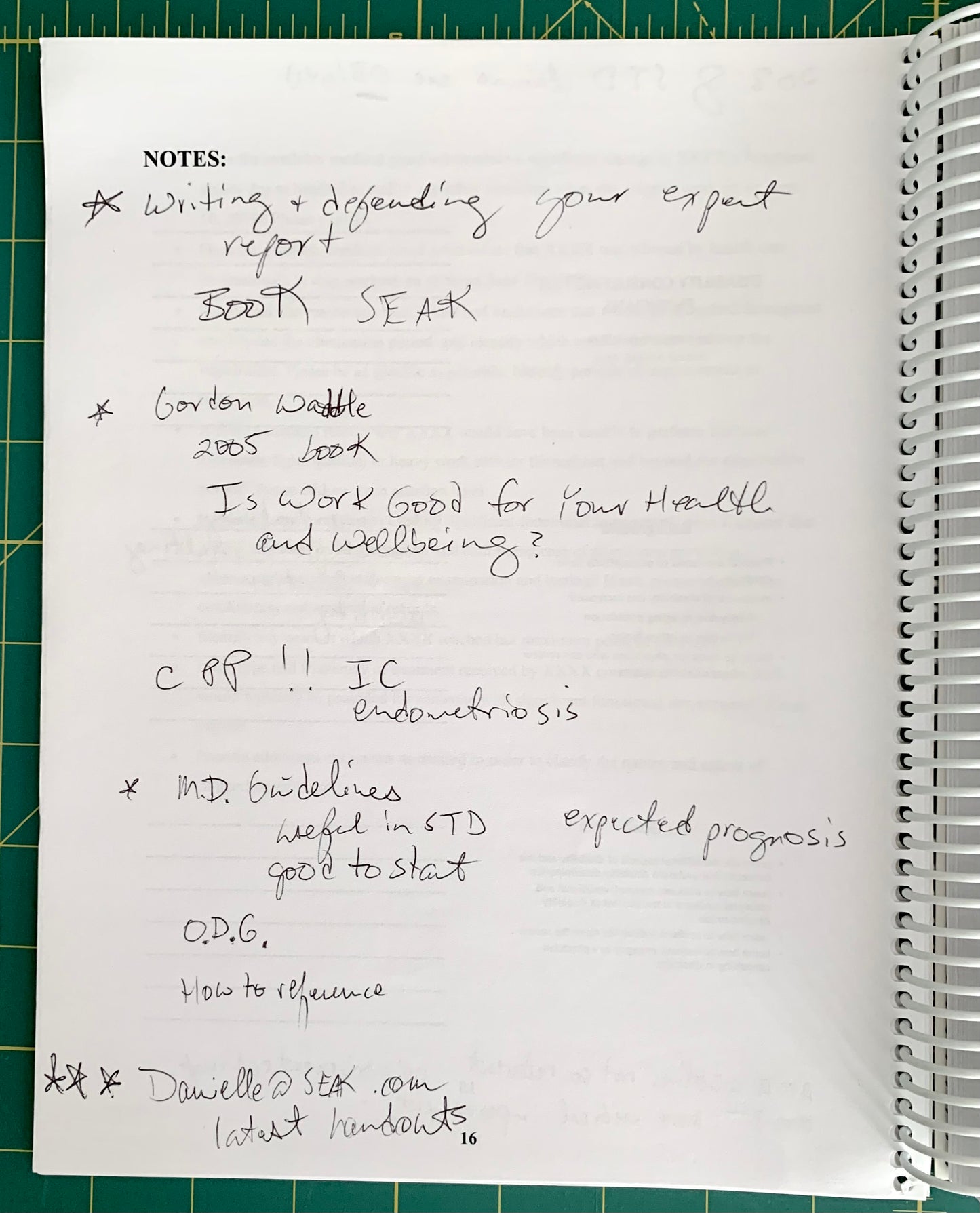 A handwritten notebook page with notes about books, health, and references, photographed on a green cutting mat next to a spiral notebook.
[additional_image_link]