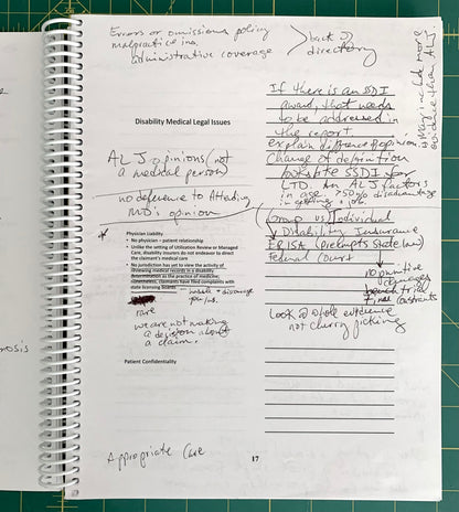 A spiral-bound notebook page filled with handwritten notes and printed legal text about disability medical legal issues, photographed on a green cutting mat.
[additional_image_link]