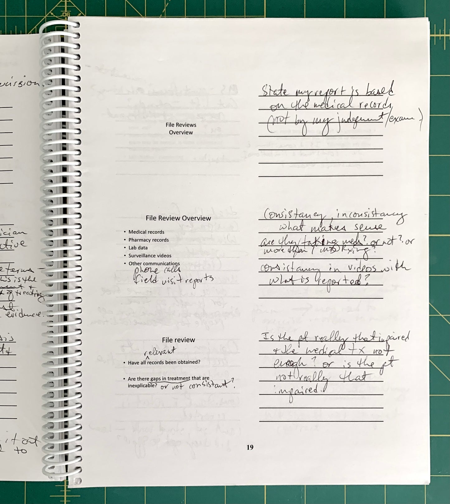 A spiral-bound notebook page with handwritten notes and printed text, photographed from above on a green cutting mat background.
[additional_image_link]