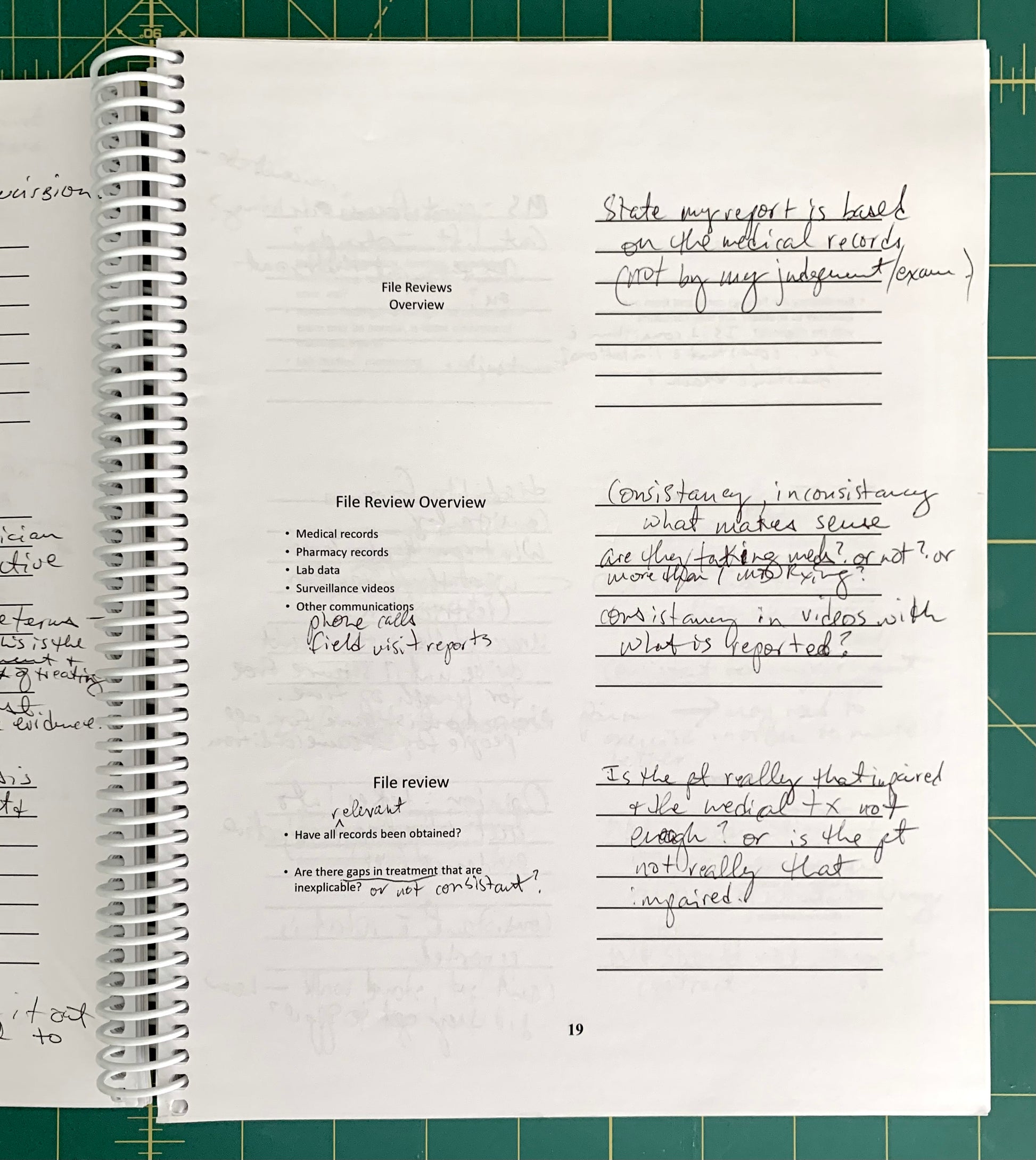 A spiral-bound notebook page with handwritten notes and printed text, photographed from above on a green cutting mat background.
[additional_image_link]