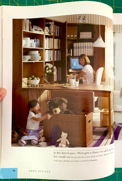 A printed interior design magazine page showing a home office layout with shelving, desk, computer, and children playing with stuffed animals in a playpen setup. The page includes a photo of the space and a block of text at the bottom.
[additional_image_link]