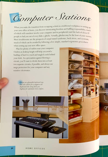 An open book or magazine spread showing a printed article titled "Computer Stations" with text, small inset photos, and a large color photograph of a home office setup on the right page. A human hand is visible holding the left edge of the page.
[additional_image_link]
