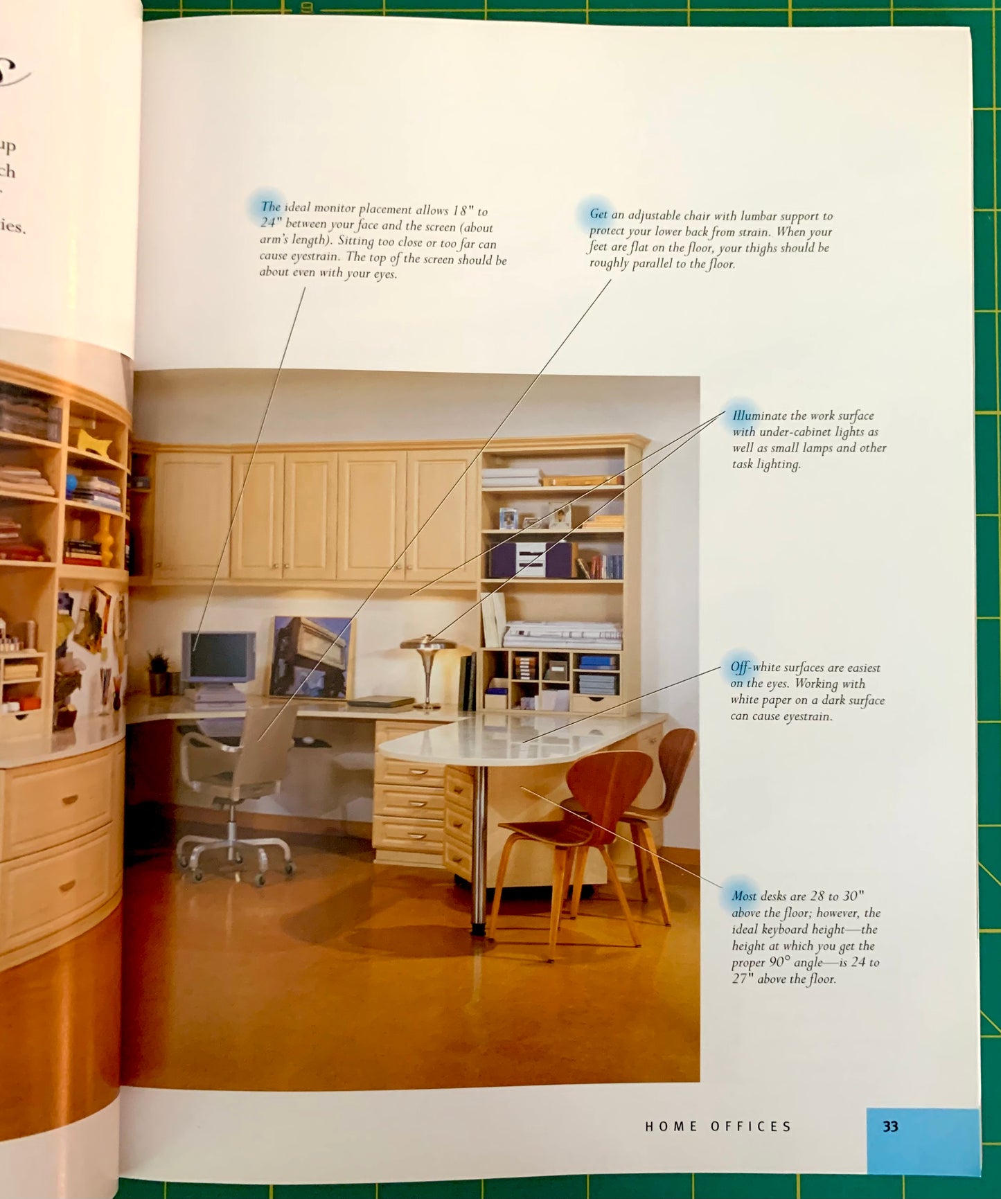 An interior page from a home decor or furniture magazine showing a furnished home office with wood cabinets, desk, chair, shelves, and text callouts explaining desk surfaces and lighting. The page is photographed on a green grid background.
[additional_image_link]