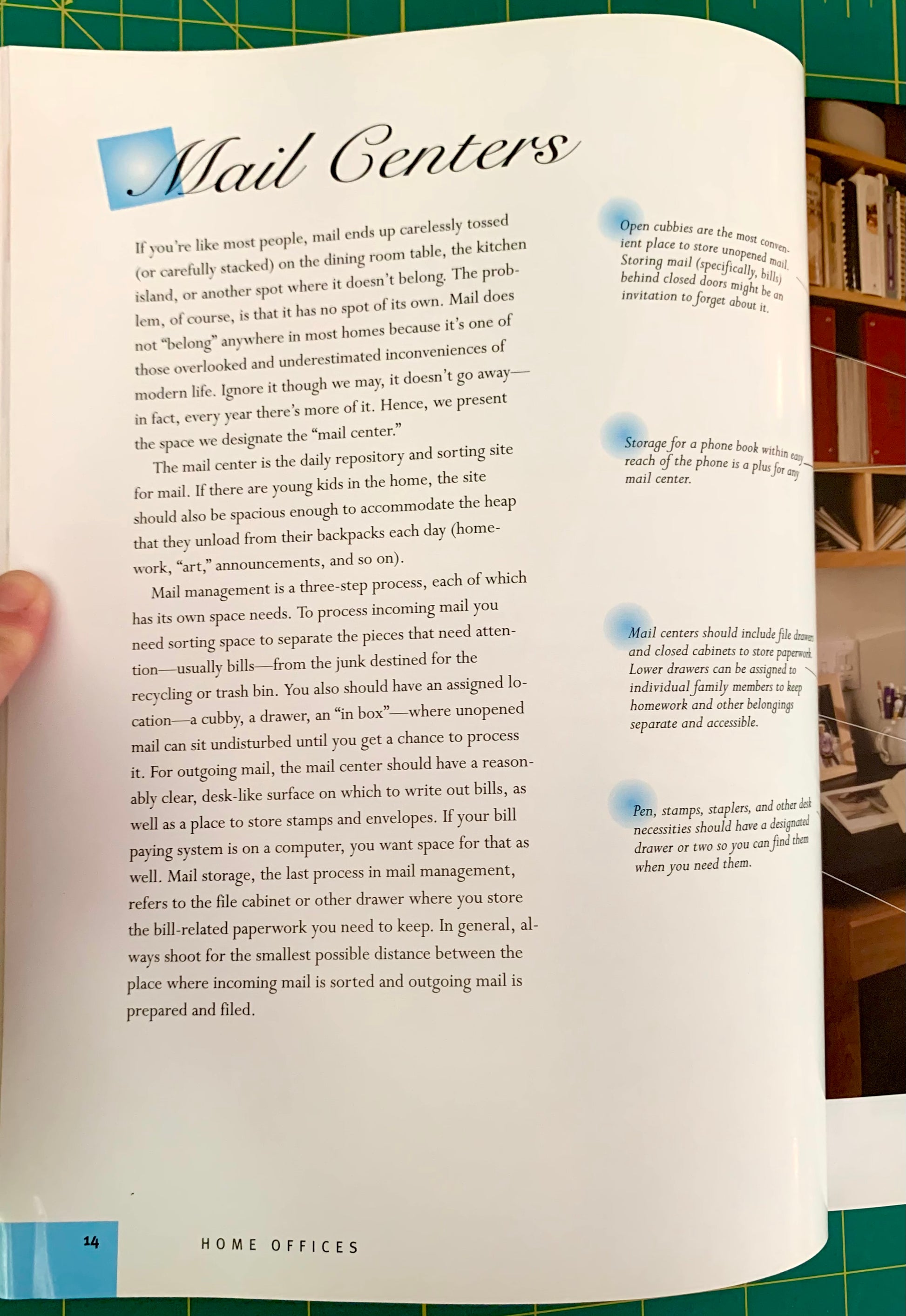 An open book page titled 'Mail Centers' with printed text and several small blue callout boxes, photographed against a green cutting mat with books visible along the right edge.
[additional_image_link]