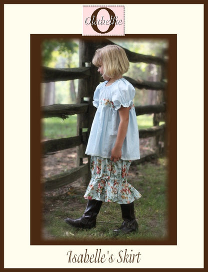 A child wearing a light blue short-sleeve top and a floral tiered skirt with dark boots, standing outdoors beside a wooden fence. The image includes a decorative border and text reading 'Isabelle's Skirt' and 'Olabelhe'.
Photo by Olabelhe [image_link]