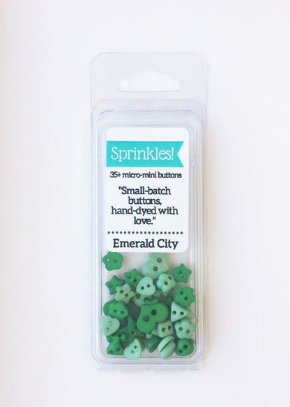 Pack of 35+ micro-mint green buttons from Sprinkles! brand, labeled 'Emerald City', in a clear plastic blister pack against a white background.