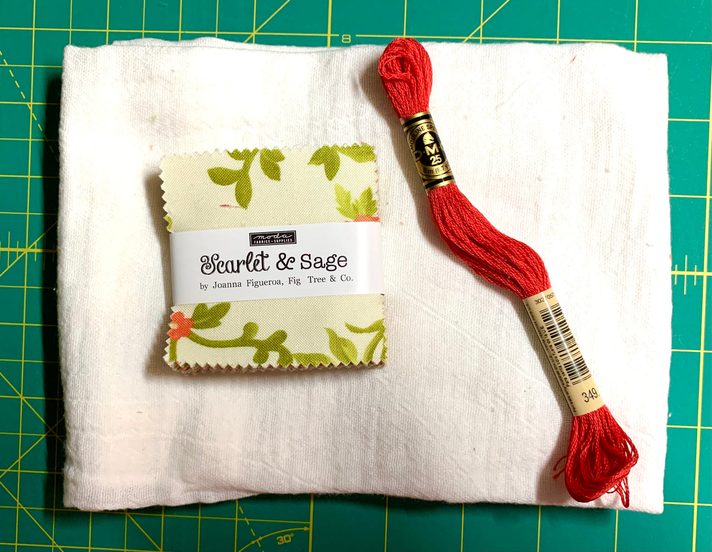 Red embroidery floss on a white fabric with a label on a green cutting mat
Photo by Karen King [image_link]
