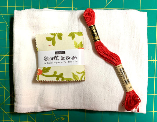 Red embroidery floss on a white fabric with a label on a green cutting mat
Photo by Karen King [image_link]