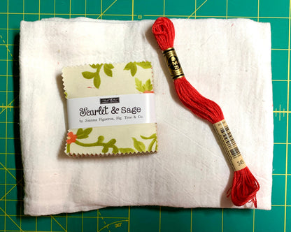 Red embroidery floss and fabric swatch on a white fabric background with a green cutting mat.
Photo by Karen King [additional_image_link]