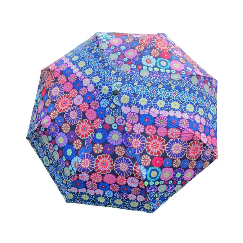 A compact octagonal umbrella with a dense, colorful floral pattern on a dark blue background, isolated on a white background.
Photo by Kaffe Fassett [additional_image_link]