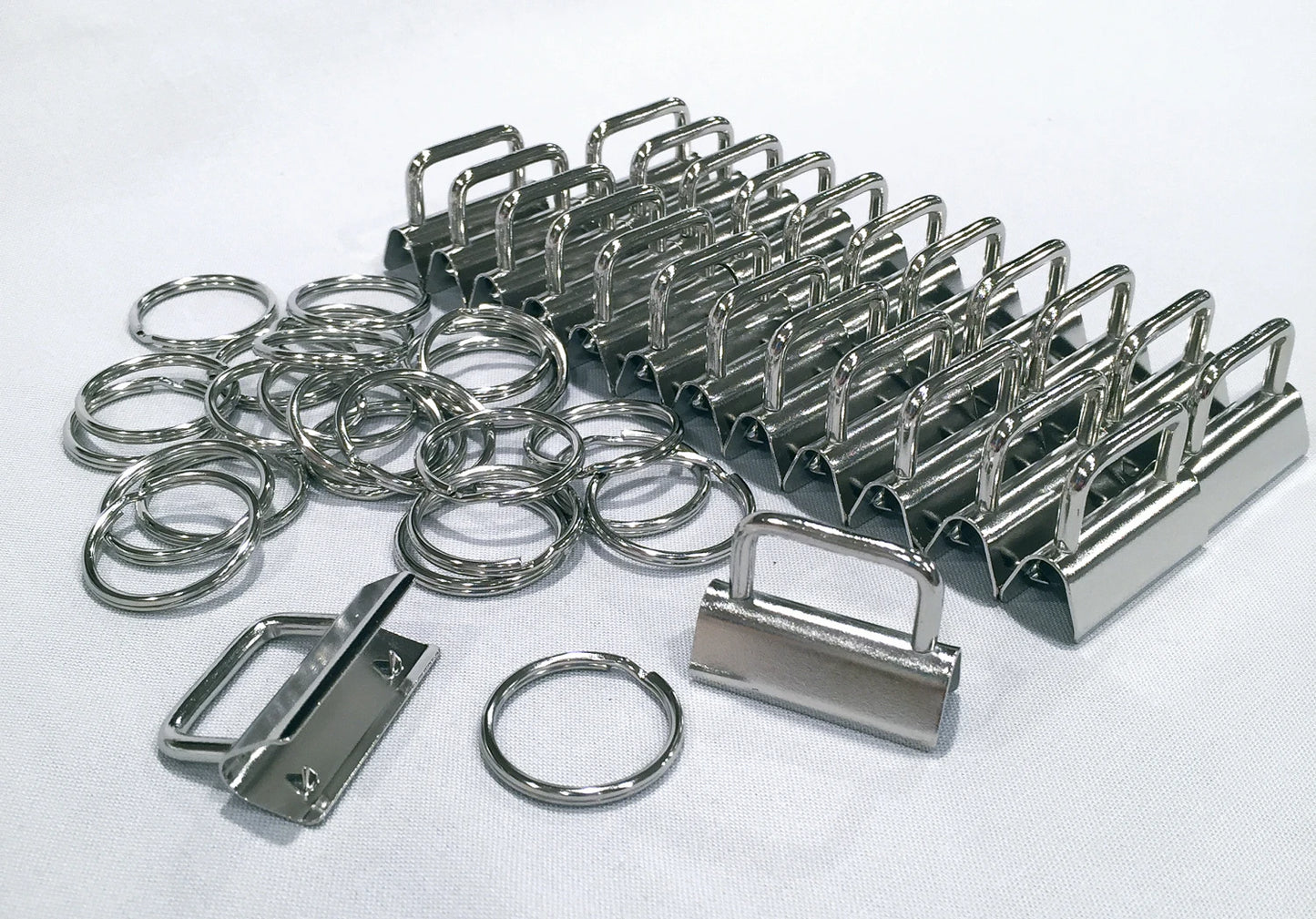 A set of polished stainless steel keyring clips and hardware pieces, including binder clips, split rings, and a padlock-shaped clip, arranged on a white textured background.
[additional_image_link]