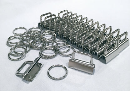 A set of polished stainless steel keyring clips and hardware pieces, including binder clips, split rings, and a padlock-shaped clip, arranged on a white textured background.
[additional_image_link]