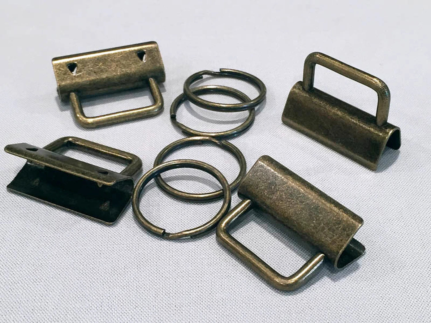 Collection of bronze metal buckles and rings on a white background.
[additional_image_link]