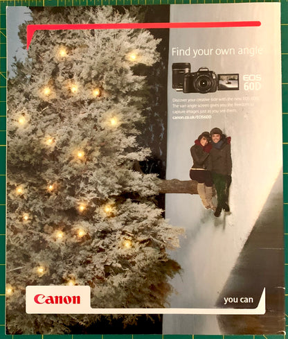 A Canon EOS 60D camera advertisement featuring a snowy Christmas tree with warm lights on the left and a couple snowboarding on the right, with the Canon logo at the bottom left.
[additional_image_link]