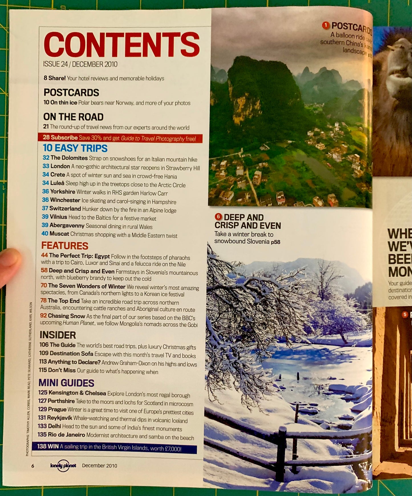 An open magazine or booklet spread showing the 'CONTENTS' page with text, a mountain landscape photo, and a travel guide cover, photographed on a green surface.
[additional_image_link]