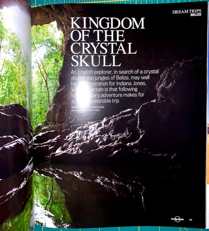 A printed travel guide or magazine page featuring a large photograph of a dark rocky cave interior with green foliage on the left and white title text reading 'KINGDOM OF THE CRYSTAL SKULL.' Smaller text appears below, and a small 'Dream Trips' mark is visible in the top right.
[additional_image_link]
