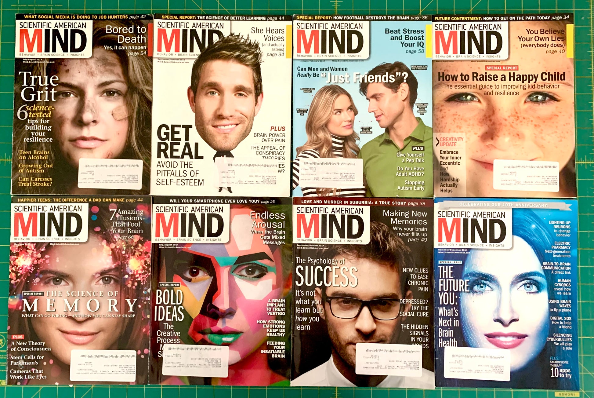 Eight copies of Scientific American Mind magazine arranged in a 2x4 grid on a green cutting mat. The covers feature various colorful portraits and article titles.
[additional_image_link]