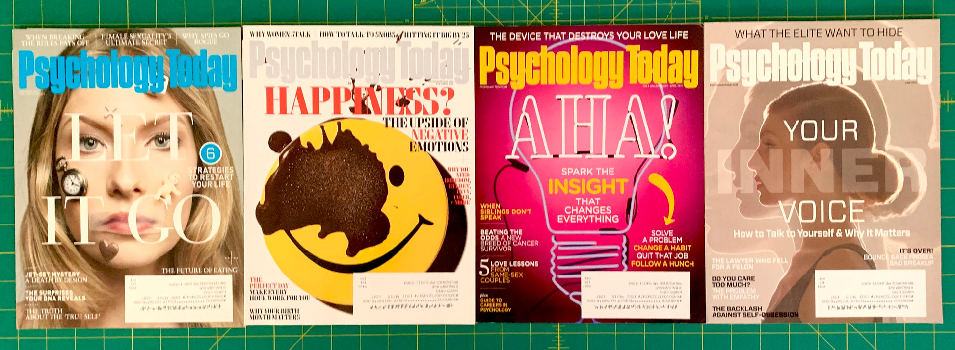 Four Psychology Today magazine covers displayed side by side on a green grid cutting mat. The covers feature different cover lines and graphics, including a woman's face, a yellow smiley face, a pink 'AHA!' cover, and a silhouette with the text 'YOUR TONE VOICE'.
[additional_image_link]