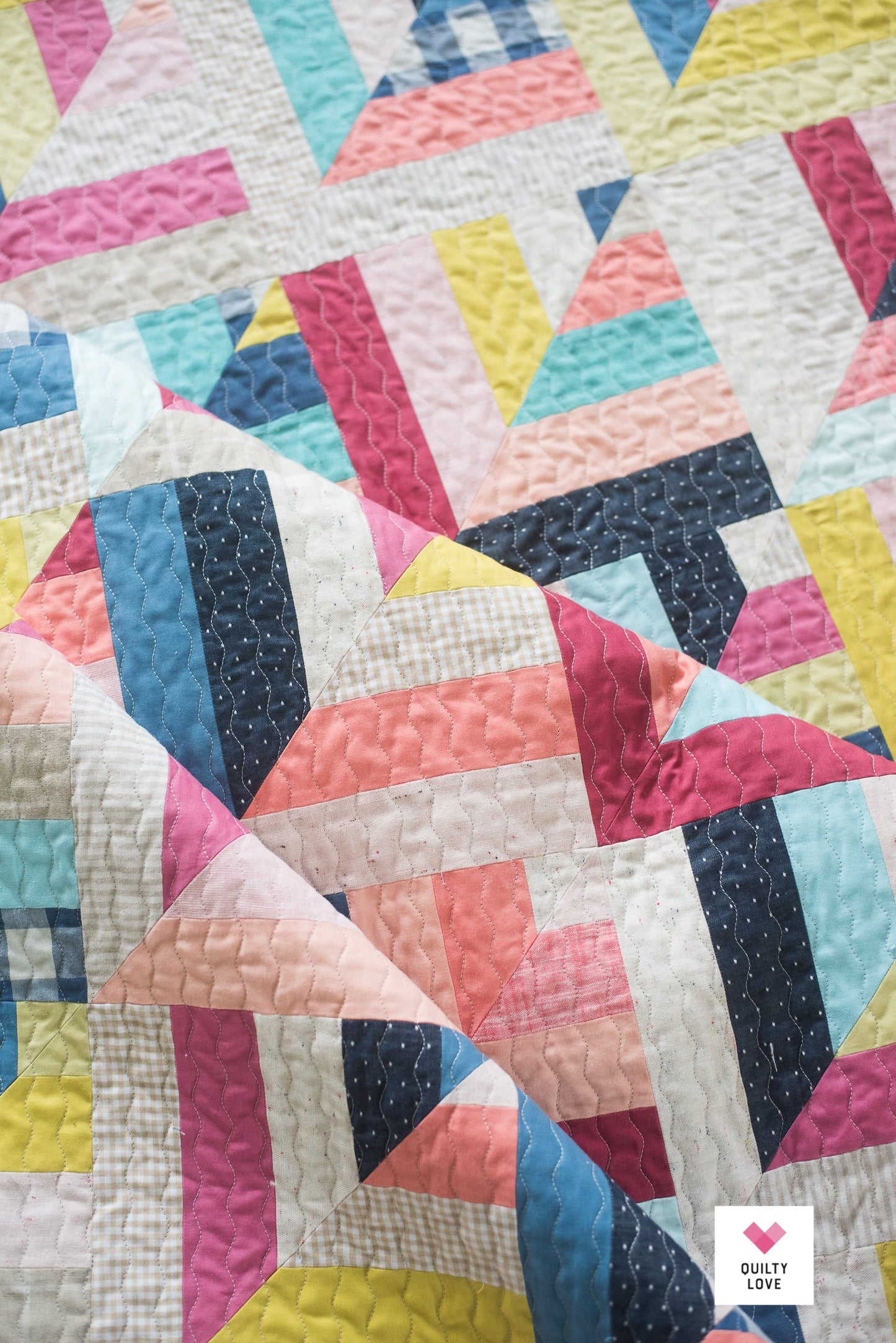 Colorful quilt with geometric pattern on a white background.
Photo by Quilty Love [additional_image_link]