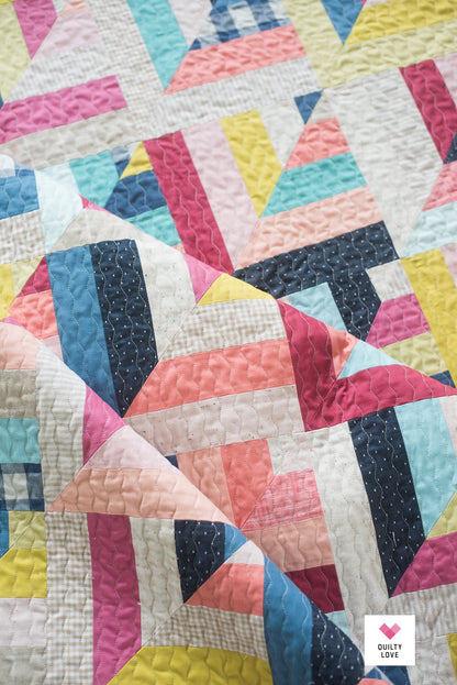 Colorful quilt with geometric pattern on a white background.
Photo by Quilty Love [additional_image_link]