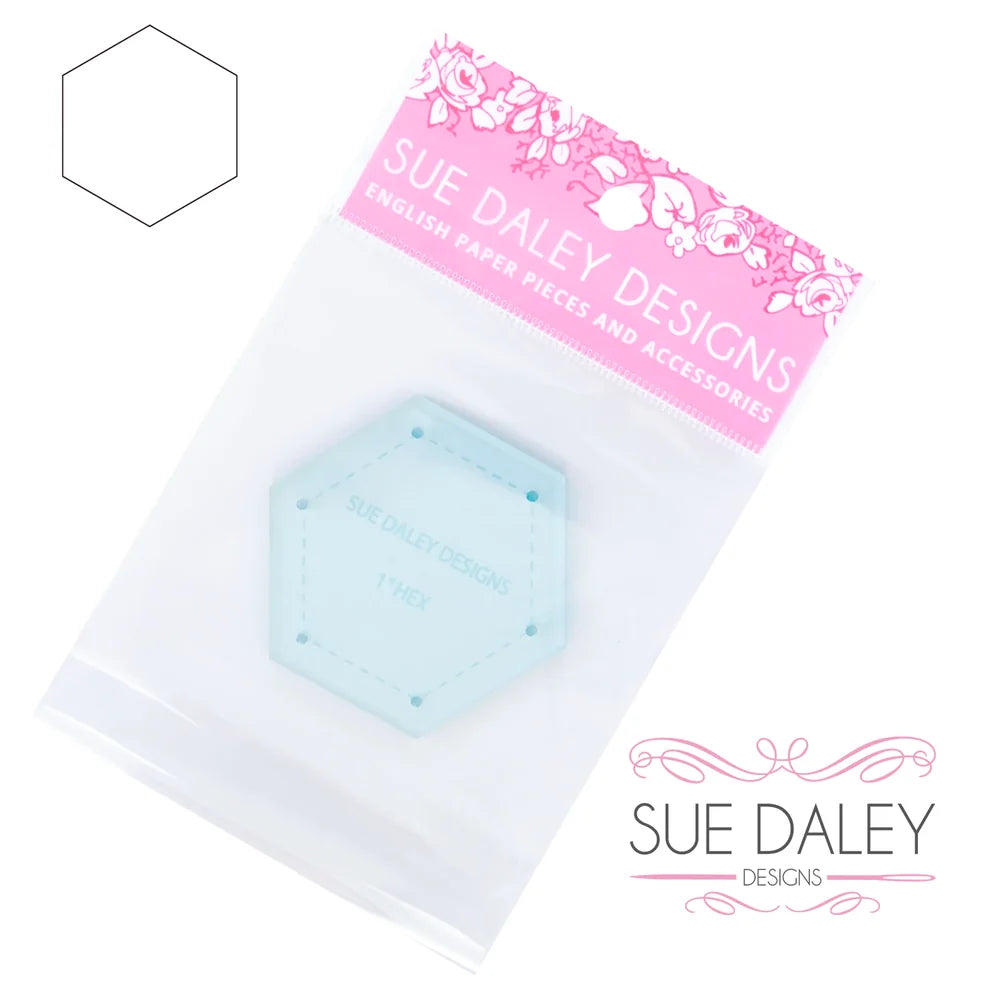 A light blue hexagonal paper clip accessory in a clear plastic bag with a pink 'SUE DALEY DESIGNS' header card, shown on a white background with the brand logo and a faint hexagon outline.
Photo by Sue Daley [additional_image_link]