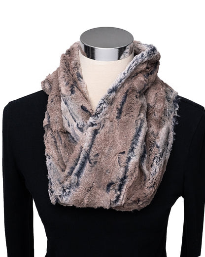 A plush faux-fur infinity scarf in a mottled taupe, brown, and gray pattern, styled on a mannequin torso wearing a black top against a white background.
Photo by Shannon Fabrics [additional_image_link]