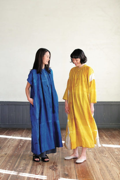 Two women wearing blue and yellow dresses standing on a wooden floor.
[additional_image_link]