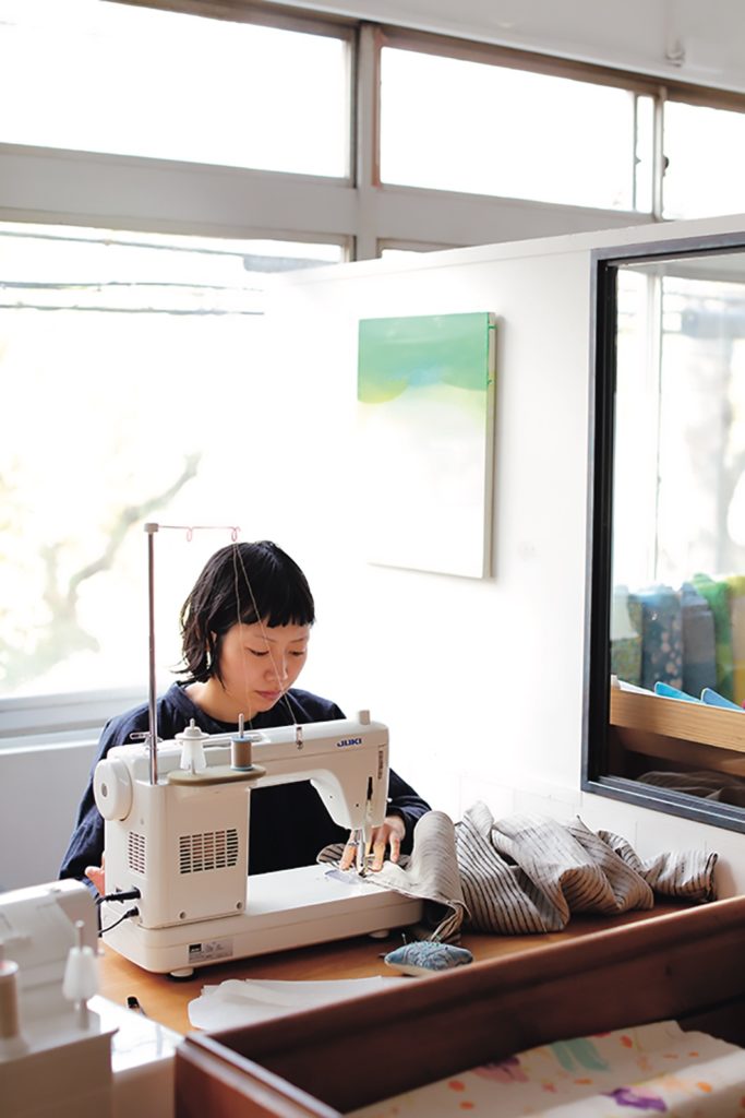 Person using a sewing machine in a bright room with large windows.
[additional_image_link]