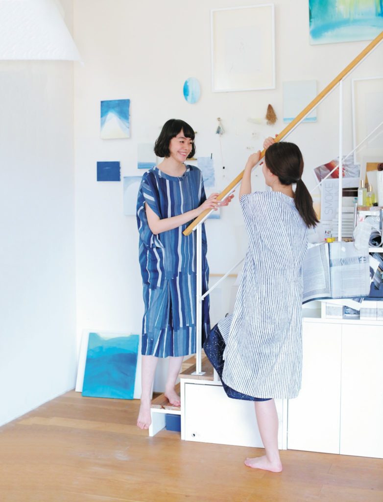 Two women in a room with blue and white decor, one holding a broom.
[additional_image_link]