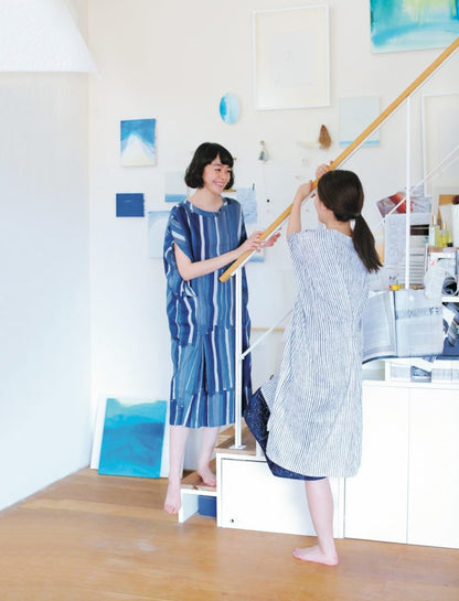 Two women in a room with blue and white decor, one holding a broom.
[additional_image_link]