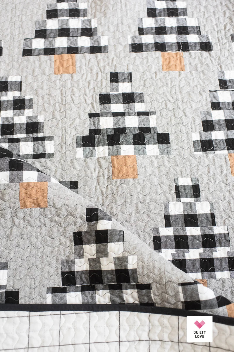 Quilt with geometric pattern featuring black, white, and brown squares on a gray background.
Photo by Quilty Love [additional_image_link]