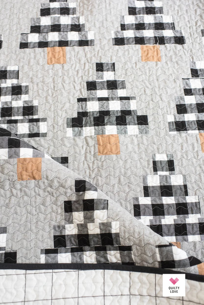 Quilt with geometric pattern featuring black, white, and brown squares on a gray background.
Photo by Quilty Love [additional_image_link]