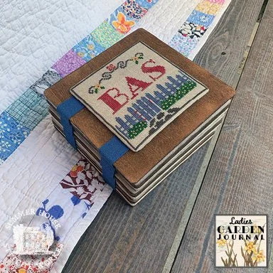 A stack of wooden coasters with a central embroidered patch with initials of the stitcher.
Photo by Summer House Stitche Workes [additional_image_link]