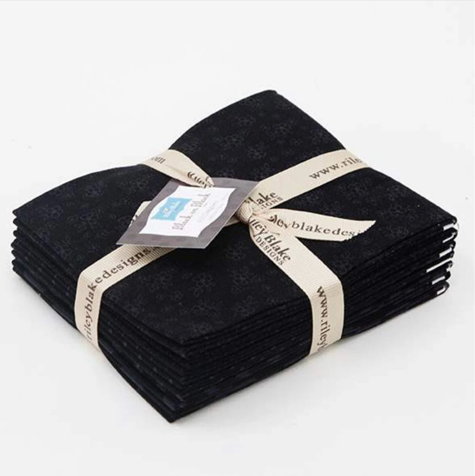 A bundle of black fat quarters with tonal prints, tied together with a ribbon and a tag displaying the brand name 'Riley Blake Designs'.
Photo by RileyBlakeDesigns.com [image_link]